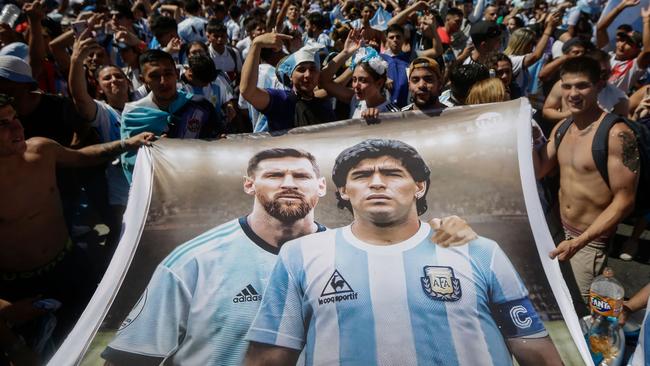 Fans of Argentina hold a flag depicting Argentine football stars Lionel Messi (L) and late Diego Maradona (R) while gathering at the Obelisk in Buenos Aires.