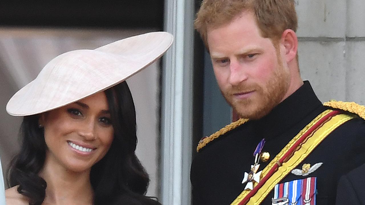 The Duchess and Duke of Sussex look at the crowds below the Buckingham Palace balcony. Picture: Mega.