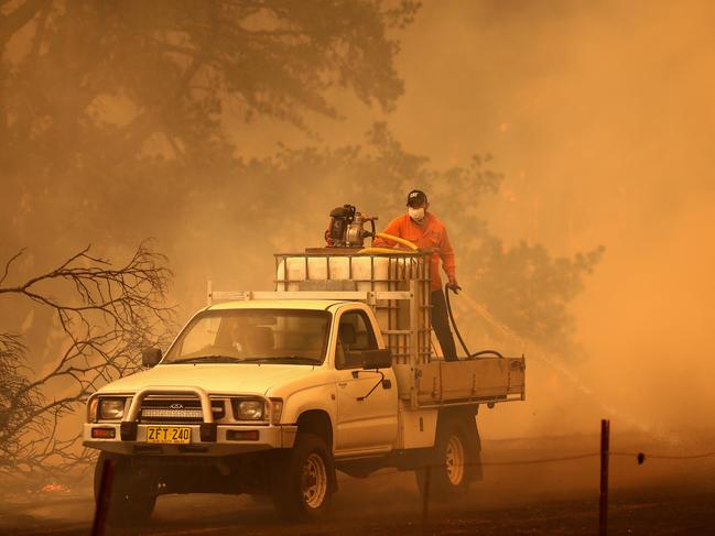 Sheldon Evans (driving) and Chris Veness (back of ute) put out spot fires near Wyndham. Picture: Toby Zerna