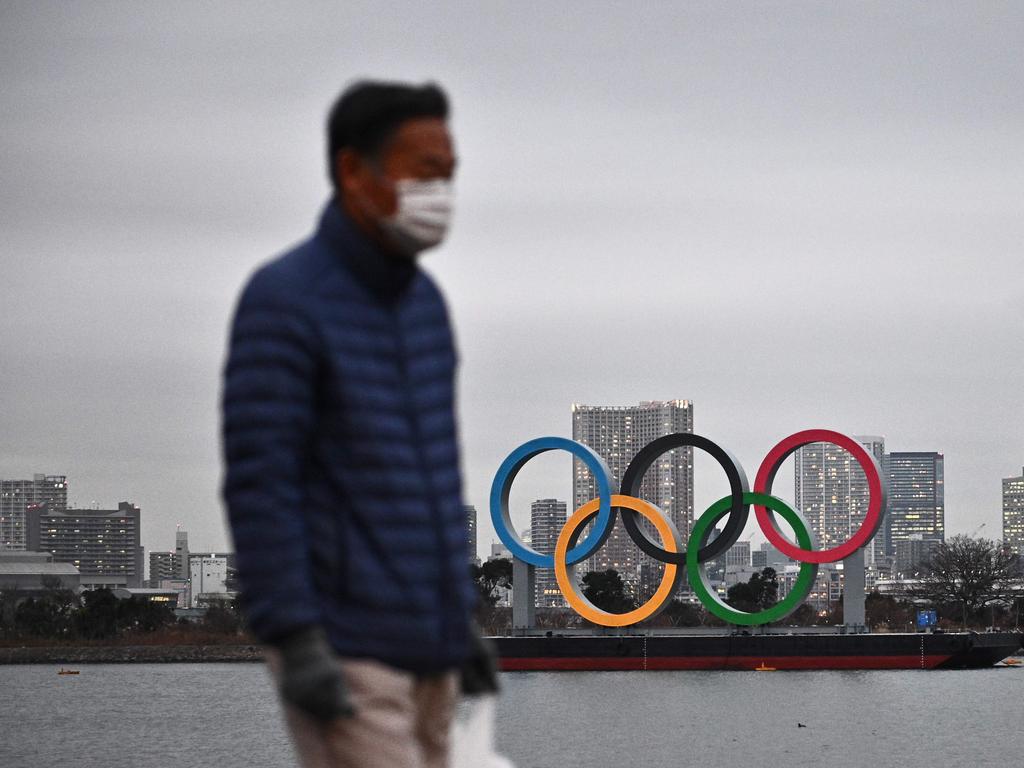 A man walks past the Olympic rings on display at the Odaiba waterfront in Tokyo.