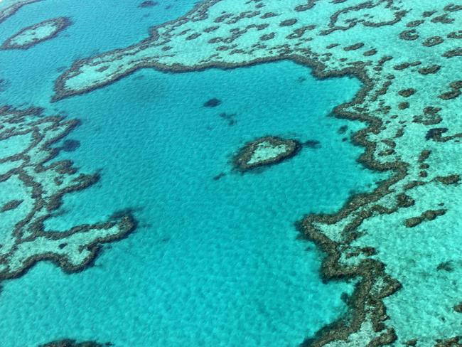 (FILES) This file photo taken on November 20, 2014, shows an aerial view of the Great Barrier Reef off the coast of the Whitsunday Islands, along the central coast of Queensland. - Climate change has become the biggest threat to UN-listed natural world heritage sites like glaciers and wetlands, and has pushed Australia's Great Barrier Reef into "critical" condition, conservationists said December 2, 2020. (Photo by Sarah LAI / AFP)