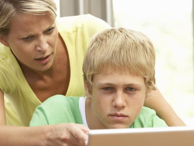 Angry Mother And Teenage Son Using Laptop At Home