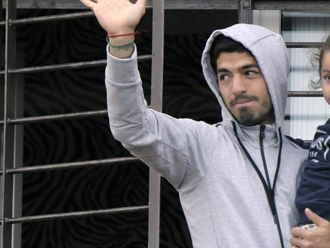 Uruguay's soccer player Luis Suarez holds his daughter as he greets fans from their home's balcony on the outskirts of Montevideo, Uruguay, Friday, June 27, 2014. Suarez returned to Montevideo early Friday, arriving too late to see the hundreds of Uruguay fans who had gathered the previous night to give him a hero's welcome despite his World Cup banishment. (AP Photo/Matilde Campodonico)