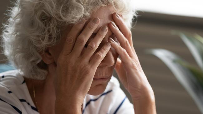 Close up 70s elderly woman sitting on sofa feels desperate crying covered face with hands, senile sickness need help, mental disorder or dementia, does not see way out difficult life situation concept  - Picture iStock
