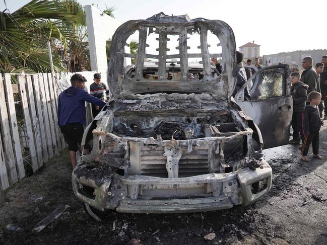 EDITORS NOTE: Graphic content / TOPSHOT - People gather around the car of the US-based aid group World Central Kitchen that was hit by an Israeli strike the previous day in Deir al-Balah in the central Gaza Strip on April 2, 2024, amid the ongoing battles between Israel and the Palestinian militant group Hamas. The international food aid charity said on April 2 it was pausing its Gaza aid operations after seven of its staff were killed in a "targeted Israeli strike" as they unloaded desperately needed food aid delivered by sea from Cyprus. (Photo by AFP)