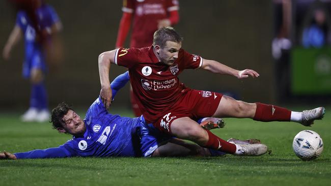 Jonny Yull of Adelaide United is taken down by Northcote City’s Leo Athanasion. Picture: Daniel Pockett