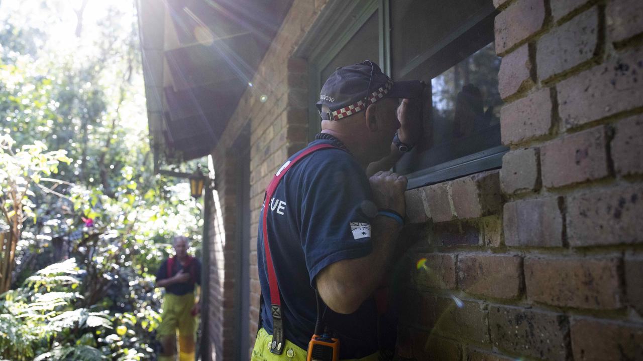 Kalorama Country Fire Authority captain Bill Robinson (left) and ex-army and CFA volunteer Shayne O'Dwyer speak to a resident through a window. Picture: Arsineh Houspian