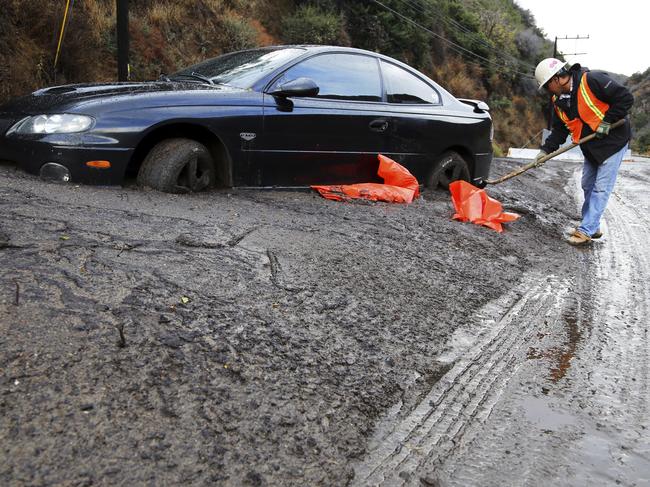 Ramon Aguayo begins to clear a car trapped in a deep debris flow that covered parts of Topanga Canyon Boulevard near the village of Topanga west of Los Angeles, Tuesday, Jan. 9, 2017. Multiple people were killed and homes were swept from their foundations as mud and debris from wildfire-scarred hillsides flowed through neighborhoods and onto a key Southern California highway Tuesday during a powerful winter storm that dropped record rain across the state. (AP Photo/Reed Saxon)