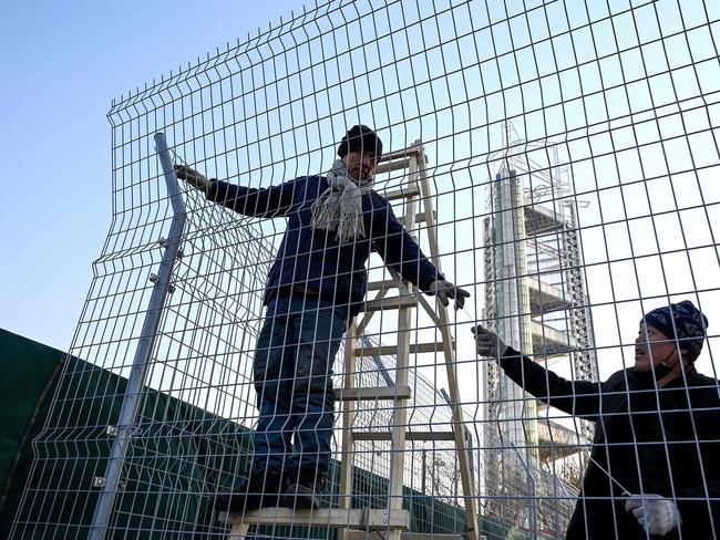 Workers use zip ties to lock up a fence to help create a "bubble" surrounding the Beijing Olympic Park in Beijing, host to the 2022 Winter Olympic Games. Picture: AFP