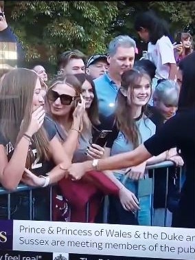 The woman (far right) bowed her head as Meghan came past.