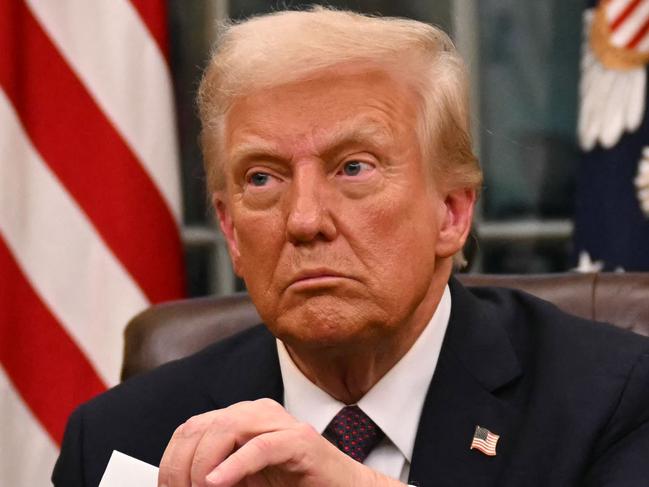 US President Donald Trump holds up outgoing President Joe Biden's letter as he signs executive orders in the Oval Office of the WHite House in Washington, DC, on January 20, 2025. (Photo by Jim WATSON / POOL / AFP) / ALTERNATE CROP