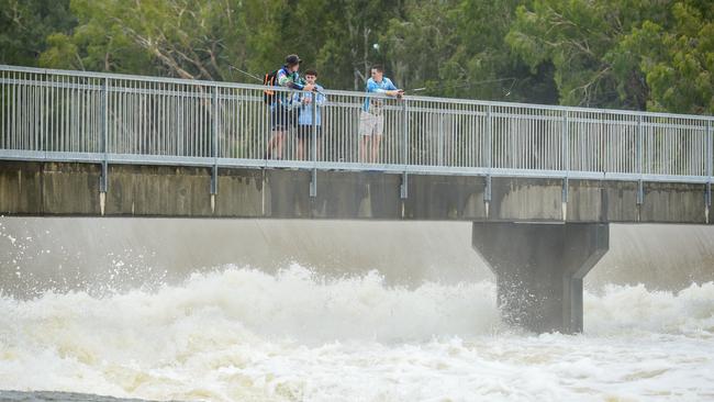 Locals fish around the raging weir in Annandale as water flows from Ross River Dam. Picture: NewsWire / Scott Radford-Chisholm