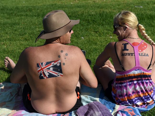 A couple with Australian flag stickers on their backs sit on the grass near Bondi Beach on Australia Day in Sydney on Tuesday, Jan. 26, 2016. (AAP Image/Paul Miller) NO ARCHIVING