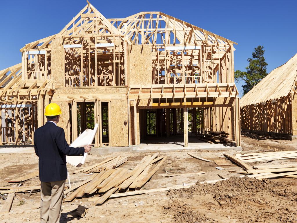 Developing Queensland - New home construction site with contractor in foreground.