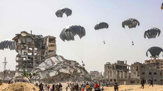 People rush for landing humanitarian aid packages dropped over the northern Gaza Strip in April. Picture: AFP