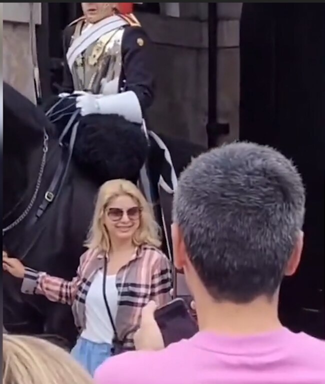 The woman poses for a photo outside Buckingham Palace.