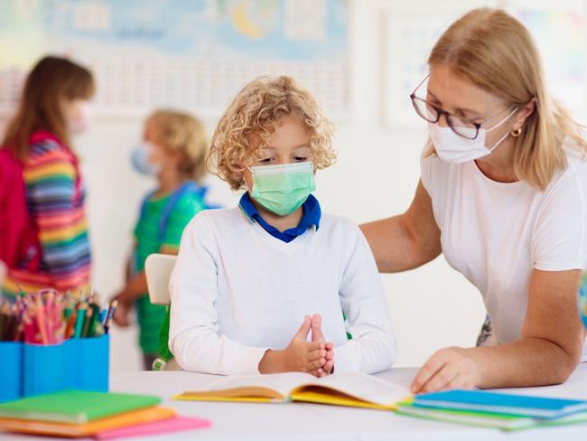 CHILDCARE/ CHILD/ YOUNG/ YOUTH -  Teacher in class, school child in face mask during corona virus and flu outbreak. Boy and girl back to school after covid-19 quarantine and lockdown. Group of kids in masks for coronavirus prevention.