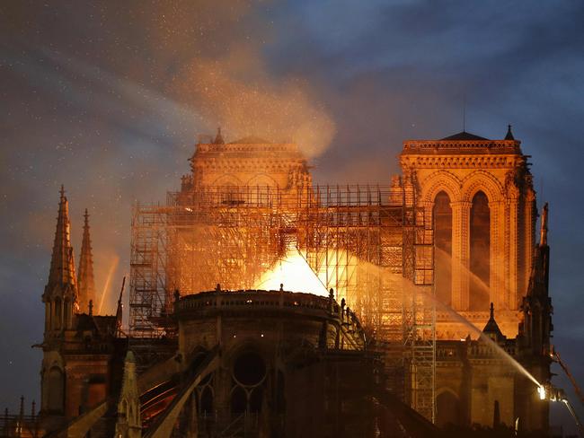 Firefighter douse flames billowing from the roof at Notre-Dame Cathedral in Paris on April 15, 2019. - A major fire broke out at the landmark Notre-Dame Cathedral in central Paris sending flames and huge clouds of grey smoke billowing into the sky, the fire service said. The flames and smoke plumed from the spire and roof of the gothic cathedral, visited by millions of people a year, where renovations are currently underway. (Photo by FRANCOIS GUILLOT / AFP)