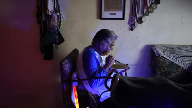 A woman eats in her house next to a motorcycle that provides her electricity. Picture: Antonio Levi/AFP