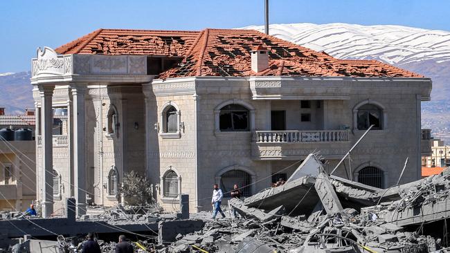 People walk past a damaged building in the aftermath of an overnight Israeli air strike on the Hezbollah stronghold of Baalbek in east central Lebanon in March. Picture: AFP