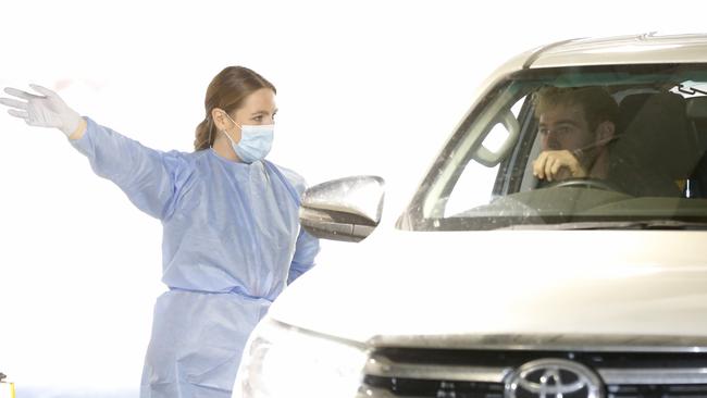 A medical worker gives instructions to David Astbury of the Tigers as he arrives to undergo drive-through COVID-19 testing at Marvel Stadium. Picture: Getty Images