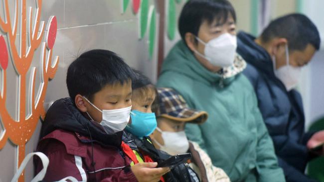 Masked children, accompanied by adults, wait to be seen by medical staff at the pediatric department of a hospital in Hangzhou, eastern China's Zhejiang province, on January 6, 2025. Beijing has acknowledged a surge in cases of the flu-like human metapneumovirus (HMPV), especially among children, and attributed this to a seasonal spike. (Photo by AFP) / China OUT