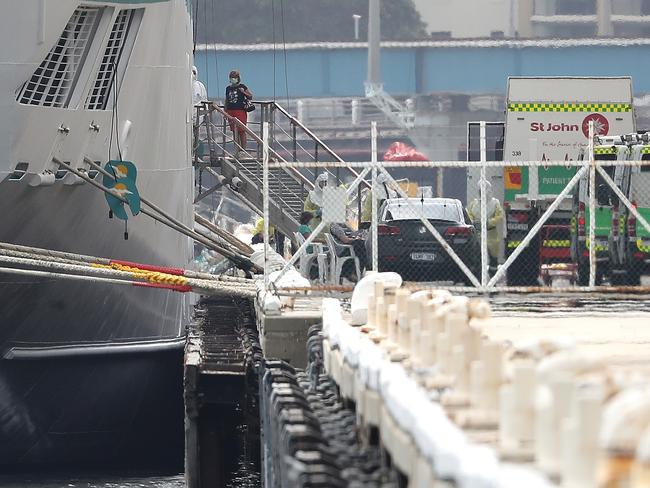 A passenger walks from the MV Artania to be attended to by waiting paramedics on the wharf at the Fremantle Passenger Terminal.