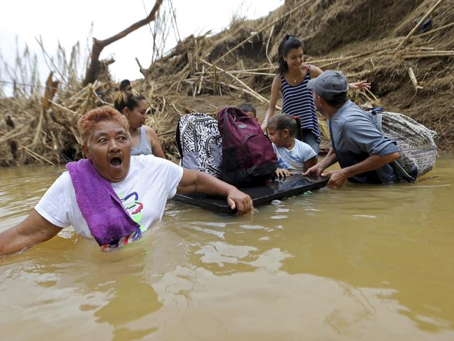 Marta Sostre Vazquez reacts as she starts to wade into the San Lorenzo Morovis River with her family in Morovis, Puerto Rico on Wednesday, September 27, after a bridge was swept away by Hurricane Maria. The family was returning to their home after visiting family on the other side. Picture: Gerald Herbert/AP