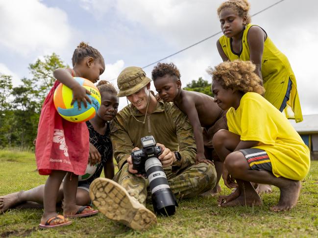 Australian Army Corporal Brandon Grey from Joint Task Group 637.3 shows children photographs on his camera at the Private Jamie Clark Memorial Kindergarten in Honiara, Solomon Islands on 13 December 2021. Photo: CPL Brodie Cross