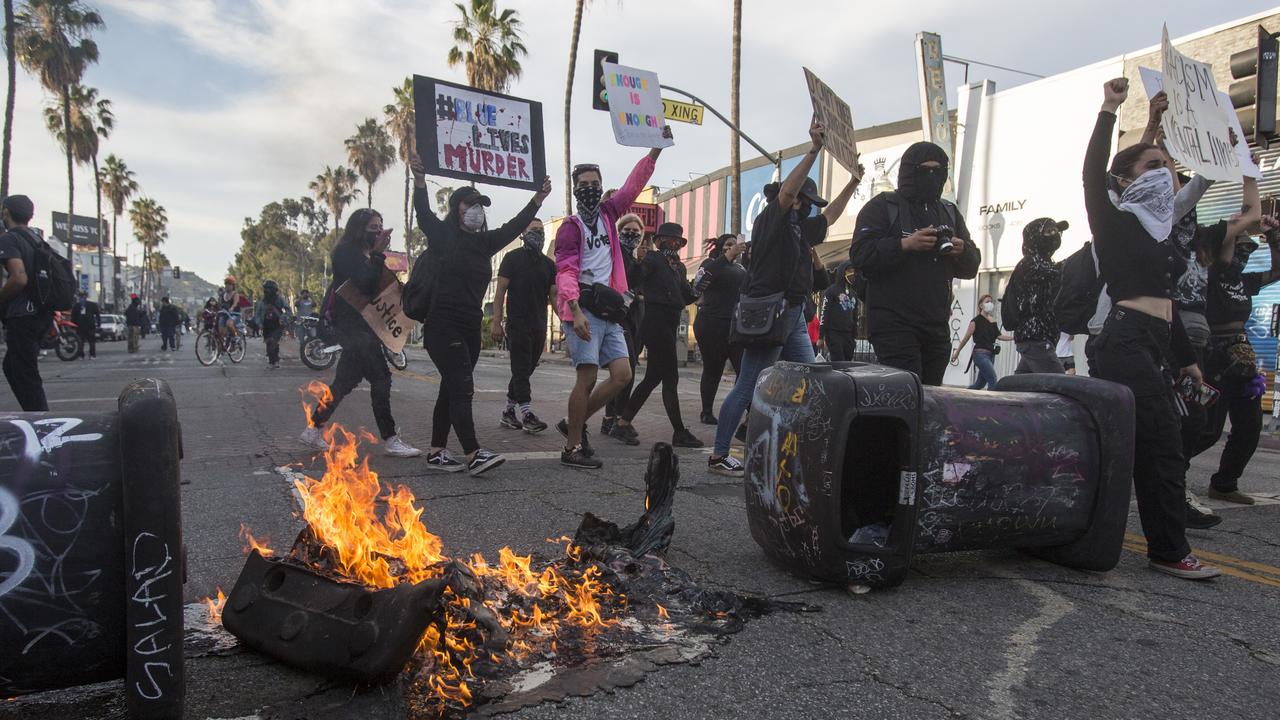 Protesters march by the burning trash cans during a protest over the death of George Floyd, a handcuffed black man in police custody in Minneapolis, in Los Angeles, Saturday, May 30, 2020. Picture: Ringo H.W. Chiu/AP