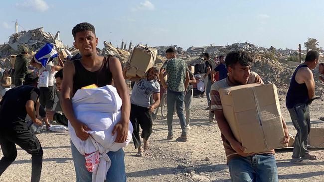 Men flinch from gunfire as they receive food packages in western Rafah. Picture: AFP