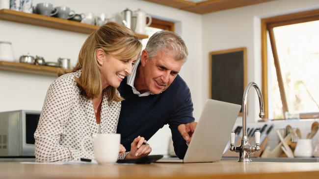 A senior couple planning their finance and paying bills while using a laptop at home. A mature man and woman going through paperwork and working online with a computer; superannuation money generic