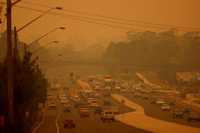 Smoke haze envelopes south western Sydney near Camden as bushfires burn. Motorists on Narellan Rd have turn their headlights on to combat the eerie orange glow. Picture: Toby Zerna