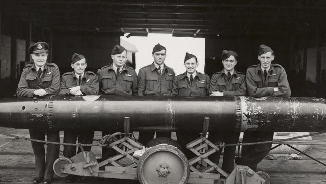 A smiling James Catanach (third from the right) poses with comrades behind a torpedo. He flew Hampden bombers, which laid sea mines and launched torpedoes as well as dropping bombs. His plane was hit by anti-aircraft fire on a mission in September 1942, but Catanach managed to save his crew by landing the struggling plane on the Norwegian shoreline instead of in the freezing Arctic waters. Picture: Australian War Memorial