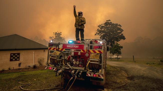 Firefighters save a home on Willinga Drive at Bawley Point on Thursday. Picture: Gary Ramage