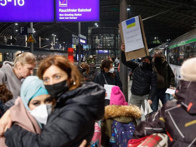 People arriving from Ukraine via Poznan, Poland, hug as a volunteer holds a placard offering help and assistance to the people who have fled the invaders. Picture: AFP