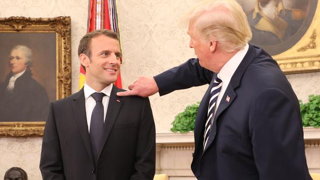 Donald Trump flicks dandruff off French President Emmanuel Macron’s collar. Picture: AFP.