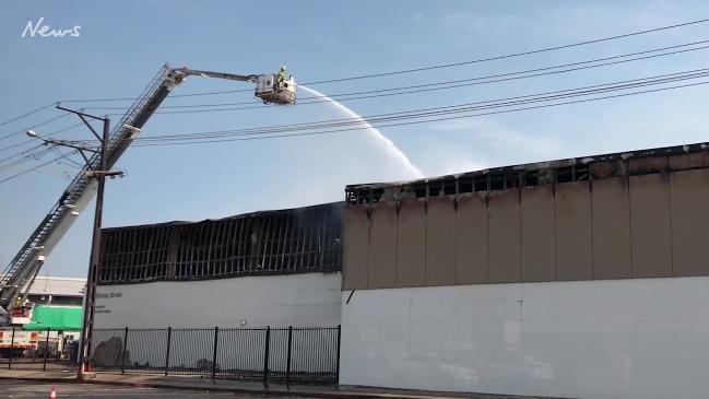 Firefighters continue to pour water into Asian United Food Service building