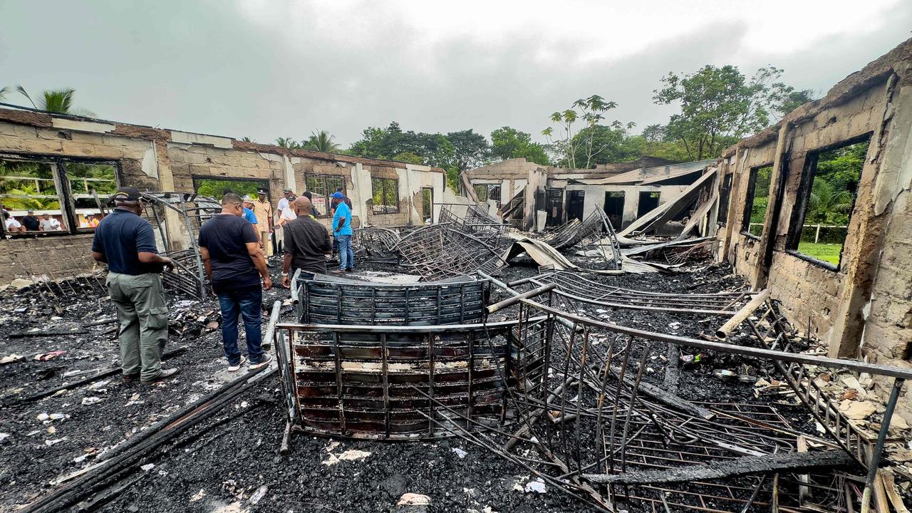 Investigators and government employees inspect the school dormitory where a fire killed at least 20 people. (Photo by Keno GEORGE / AFP)