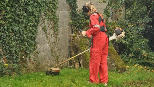 Laura using an industrial whipper-snipper to trim the grass.