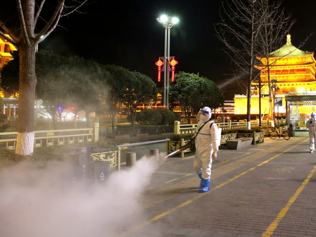 Staff members in protective suits disinfect around Xi'an Bell Tower.