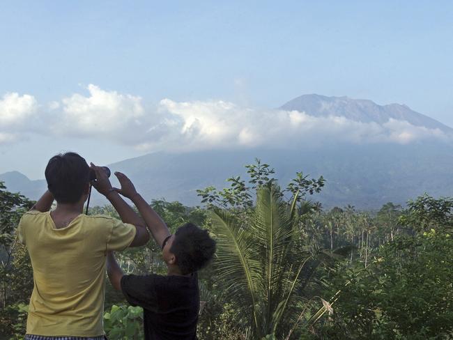 A man observes the Mount Agung with binoculars at a viewing point in Bali after officials have more than doubled the size of evacuation zone around the volcano. Photo: AP Photo/Firdia Lisnawati