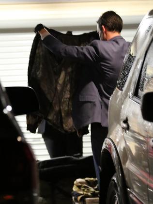 A detective holds up a camouflage suit.