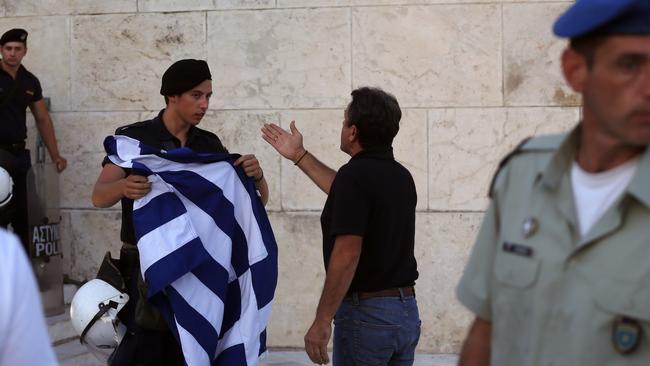 An anti-austerity protester reacts as riot police not allowed him to place a Greek flag at the one of the entrances of the Greek Parliament during a rally against the government's agreement with its creditors.