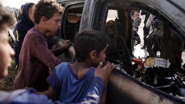 People gather around the carcass of a car used by the aid group World Central Kitchen that was hit by an Israeli strike in Deir al-Balah in the central Gaza Strip on April 2. Picture: AFP