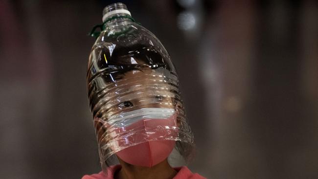 A Chinese girl wears a plastic bottle as makeshift homemade protection and a protective mask while waiting to check in to a flight at Beijing Airport.