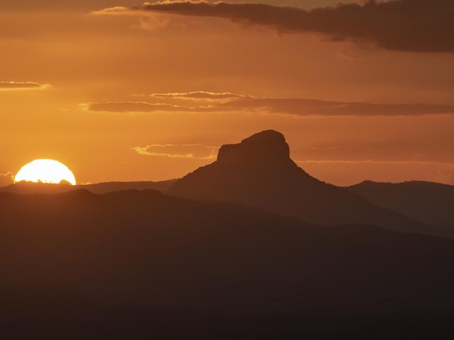 Wollumbin {Mt Warning} at sunset. It has traditional significance to the local Bundjalung people. The local Aboriginal name for the mountain is "Wollumbin"; meaning, "cloud-catcher", or alternatively "fighting chief of the mountains". The mountain's English name was bestowed on it by Lieutenant James Cook in May 1770, as his expedition in command of the Endeavour passed it by on their route northwards along the eastern coastline of Australia. The designation "Mount Warning" was meant to indicate the danger of the offshore reefs they encountered.  The Park is part of the Shield Volcano Group of the World Heritage Site Gondwana Rainforests of Australia inscribed in 1986 and added to the Australian National Heritage List in 2007. It is in NSW but this view is from the Lamington National Park in Queensland. It is part of the Border Ranges Caldera.