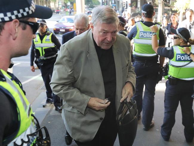 Cardinal Pell is escorted into court by a human shield of police officers. Picture: David Crosling