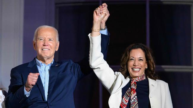 US President Joe Biden (L) and US Vice President Kamala Harris hold hands and gesture as they watch the Independence Day fireworks display from the Truman Balcony of the White House in Washington, DC, on July 4, 2024. (Photo by Mandel NGAN / AFP)