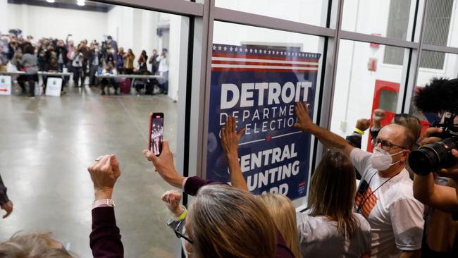 Donald Trump bang on the glass and chant slogans outside the room where absentee ballots are being counted at TCF Center in Detroit, Michigan. Picture: AFP.